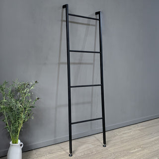 Black metal blanket ladder against a gray wall with a plant on a wooden floor.
