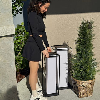 Woman placing modern solar lanterns on patio