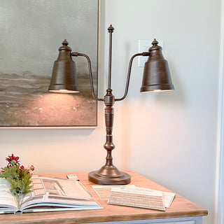 Vintage distressed bronze double arm desk lamp with adjustable shades on wooden desk with books