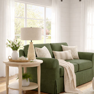 Green sofa in a living room with a side table and lamp
