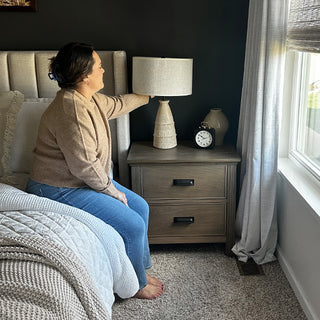 Woman adjusting modern ceramic bedside table lamp

