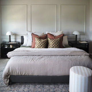 Matching white mushroom bedside lamps on black nightstands flanking upholstered bed with decorative pillows