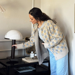 Woman adjusting modern mushroom table lamp with white dome shade on bedroom nightstand