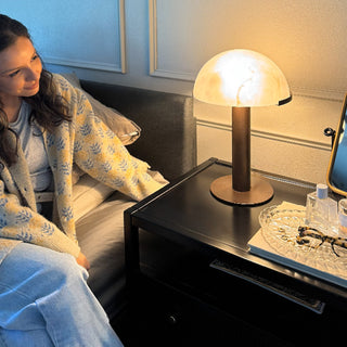 White mushroom lamp illuminated on black nightstand creating warm ambient bedroom lighting