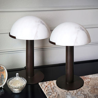 Close-up of two modern mushroom lamps with white resin dome shades and bronze cylindrical bases
