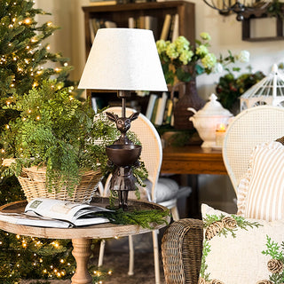 Bronze female deer table lamp on rustic round table with greenery and Christmas tree in background