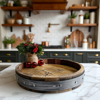 Rustic whiskey barrel lazy susan centerpiece with holiday greenery on white marble kitchen counter