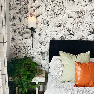 Battery wall sconce with white fabric shade creating ambient lighting in bedroom with floral wallpaper