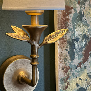 Close up of cast iron botanical wall sconce with textured leaf detail and gold finish