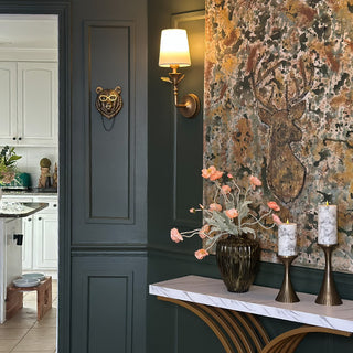 Designer wall sconces flanking abstract art in sophisticated dining room with green walls