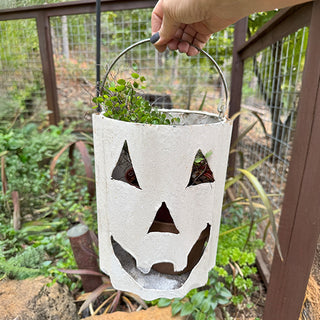 Hand holding white metal jack-o’-lantern lantern with handle