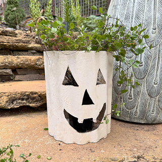 Rustic metal jack-o’-lantern planter with greenery