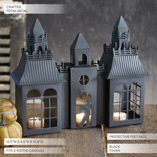 Gothic haunted house candle lantern in black metal finish, designed to fit three votive candles, with Frankenstein silhouette cutout