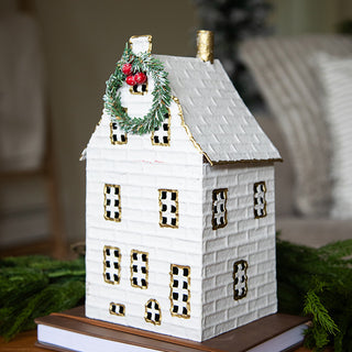 Close-up of white metal holiday house lantern with wreath and red berry accents for Christmas home décor