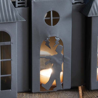 Close-up of Frankenstein silhouette cutout on haunted house metal candle holder with tealight candle glowing behind