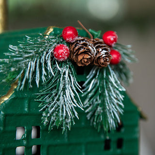 Detailed view of frosted pine, pinecones, and red berries on green metal house Christmas decoration