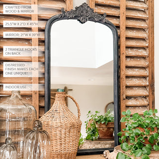 Close-up detail of distressed black finish ornate baroque crest on arched mirror frame