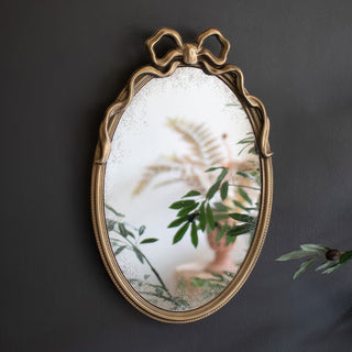  French-inspired oval mirror with gold finish reflecting greenery and home decor in elegant interior