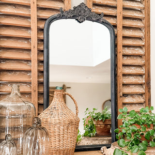 Full view of 45 inch tall arched black mirror with ornate top crest on wood shutter backdrop