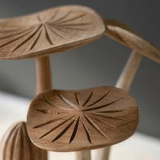Close up detail of hand-carved teakwood mushroom caps showing intricate radial line carving pattern