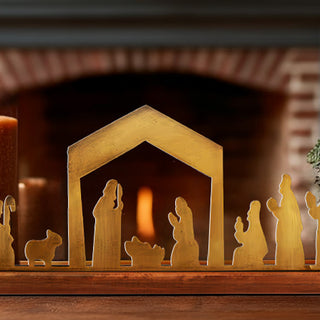 Close-up of brass nativity figures in front of fireplace, rustic Christmas home décor with warm holiday ambiance
