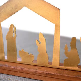 Detail view of brass nativity silhouette showing holy family figures on wooden base, handcrafted Christmas décor piece