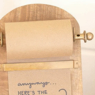 Side view of natural wood recipe roll holder showing kraft paper and handwritten recipe note