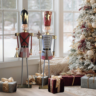Set of metal Christmas nutcracker figurines displayed beside a decorated Christmas tree and wrapped gifts in a cozy holiday living room.
