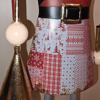 Close-up of nutcracker skirt featuring red and white patchwork holiday patterns with reindeer, trees, and snowflake designs.