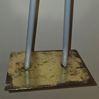 Close-up of the metal base and legs of a nutcracker figurine with a distressed gold finish.