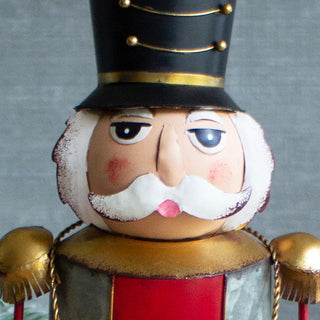 Close-up of tall nutcracker Christmas figurine with black hat, red coat, and white mustache for festive home decoration