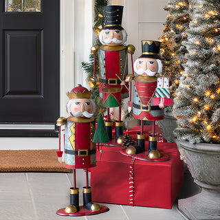 Christmas porch decorated with nutcracker figurine set, gift boxes, garland, and holiday lights beside a Christmas tree