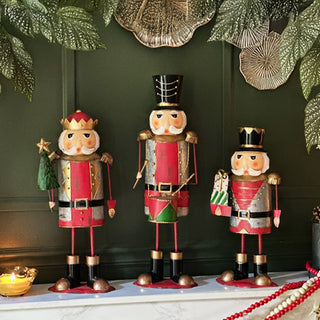 Traditional nutcracker Christmas figurines in red, green, and gold, displayed on a holiday mantel with festive greenery and garlands