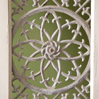 Close-up detail of hand-crafted metal floral medallion with lattice pattern on distressed white wood panel