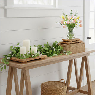 Set of three natural wood pedestal risers displayed with candles and greenery on farmhouse console table