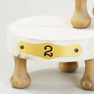  Detail of medium pedestal riser with gold number 2 plate and distressed white wood finish