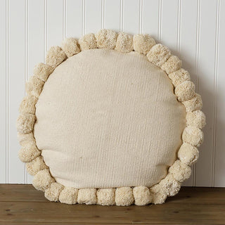 Round cream pom pom decorative throw pillow on white beadboard wall showing 18 inch diameter circular design with full pom pom border
