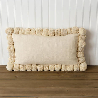 Rectangular cream pom pom lumbar pillow on white beadboard background showing 19 by 11 inch dimensions with textured fabric and pom pom detail