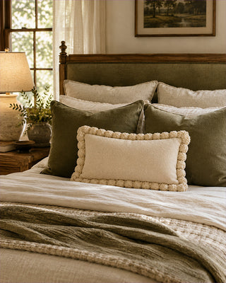 Neatly made bed with decorative pillows in a bedroom setting.
