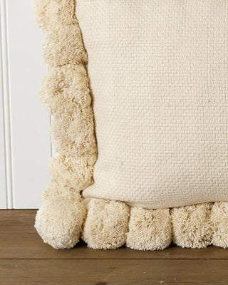 Decorative pillow with textured border on a wooden surface