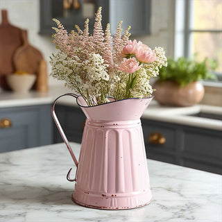  Distressed pink metal pitcher vase with fresh flower arrangement on marble countertop