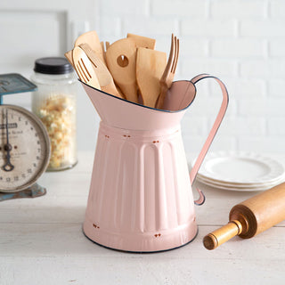 Farmhouse pink metal pitcher used as kitchen utensil holder on white countertop