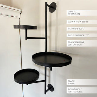 Black iron three-tier wall-mounted plant stand with adjustable trays shown against a white wall with product dimensions