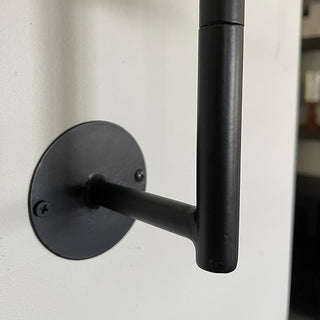 Detail shot of the black metal mounting bracket securing the wall-mounted plant stand.