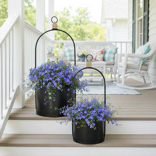 Set of two graduated black metal planters with purple flowers on patio