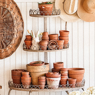 A plant stand with pots and a bunny figurine on it.