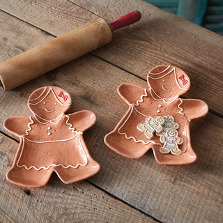 Two gingerbread girl plates with cookies on table