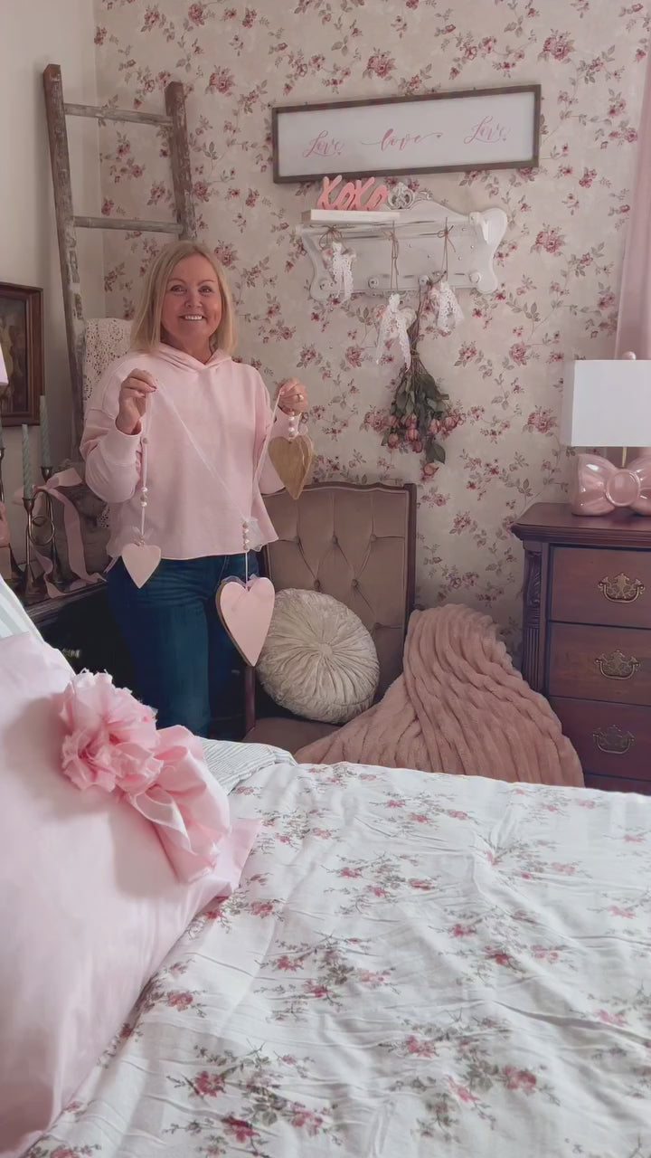 Distressed white ornate wall shelf with hooks displaying Valentine's Day hearts and dried roses