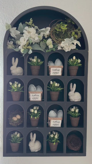 arch wall shelf filled with faux potted plants and bunny figurines