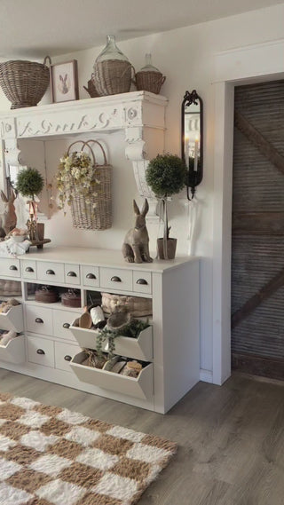 bow gold candle holders on a white console table with a white mantel shelf and bow gold scones on the wall and bunny decor